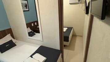 A hotel room with a bed, a mirror, a TV, and a small table.