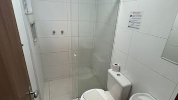 Baño con ducha, inodoro, lavamanos y cubo de basura.