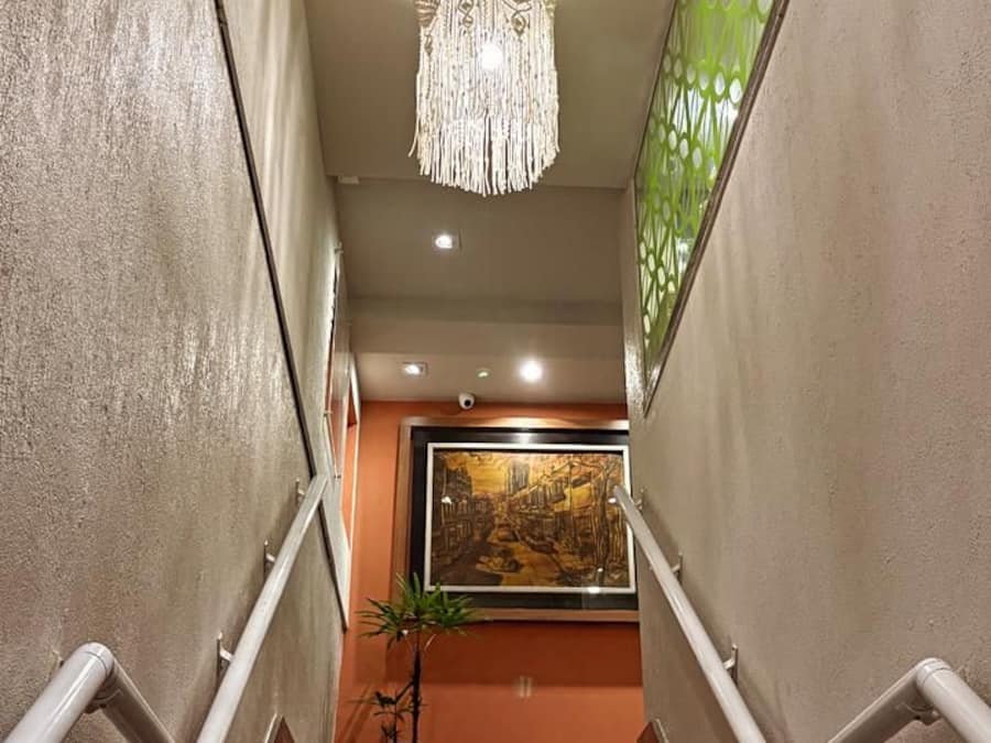 Una scala con gradini in marmo, un lampadario e un quadro appeso al muro.