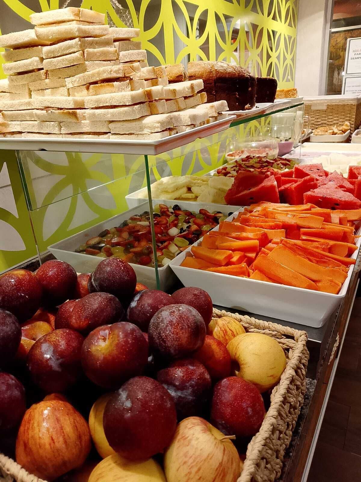 Un bufé con diversas opciones de comida, incluyendo frutas, verduras y pan.