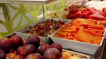 Un bufé con diversas opciones de comida, incluyendo frutas, verduras y pan.