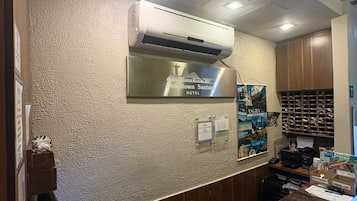 Una recepción de hotel con una computadora, un teléfono de escritorio y un aire acondicionado instalado.