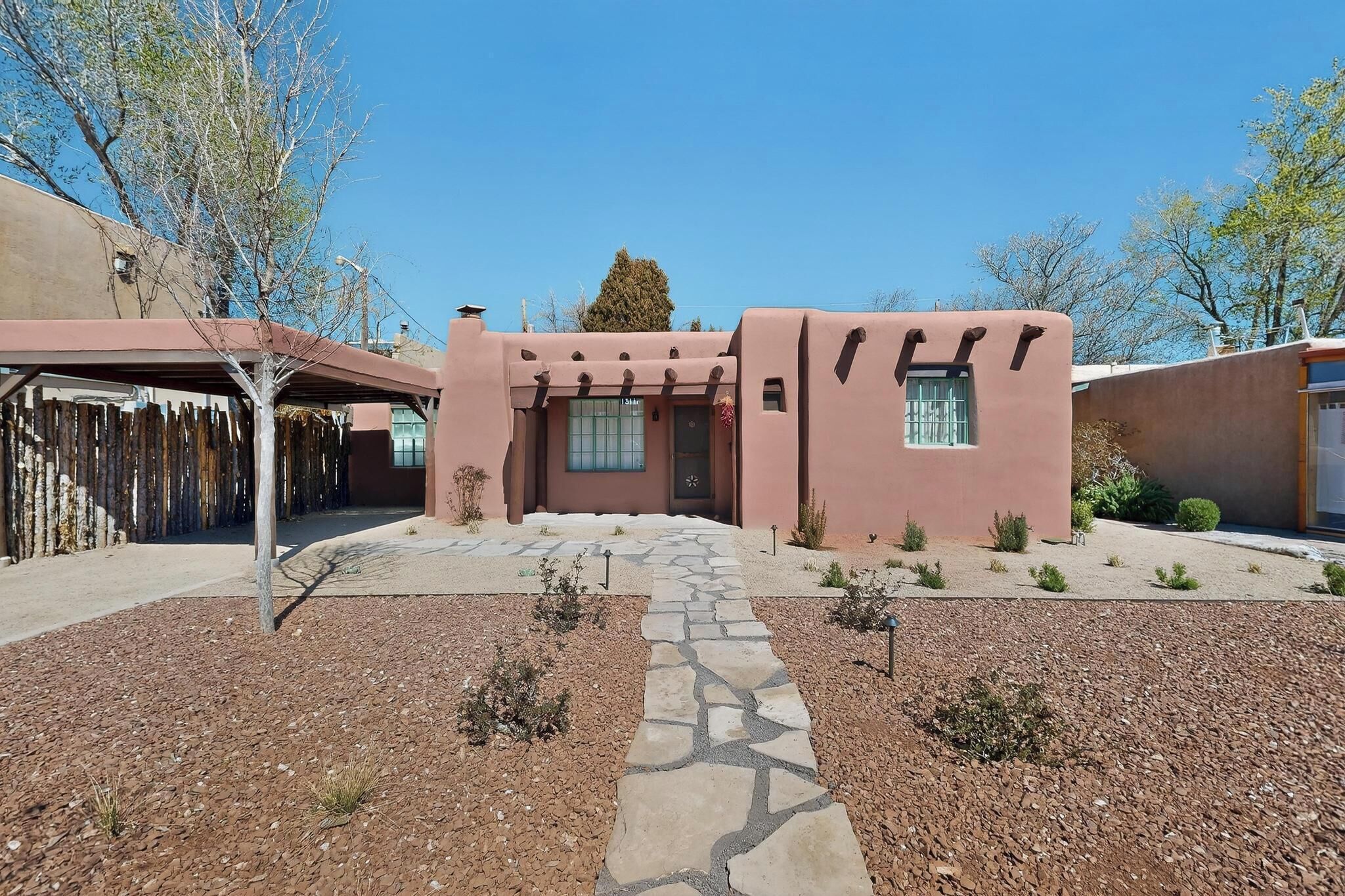 A building with a unique architectural style, a stone pathway leading to the entrance, and a clear blue sky.