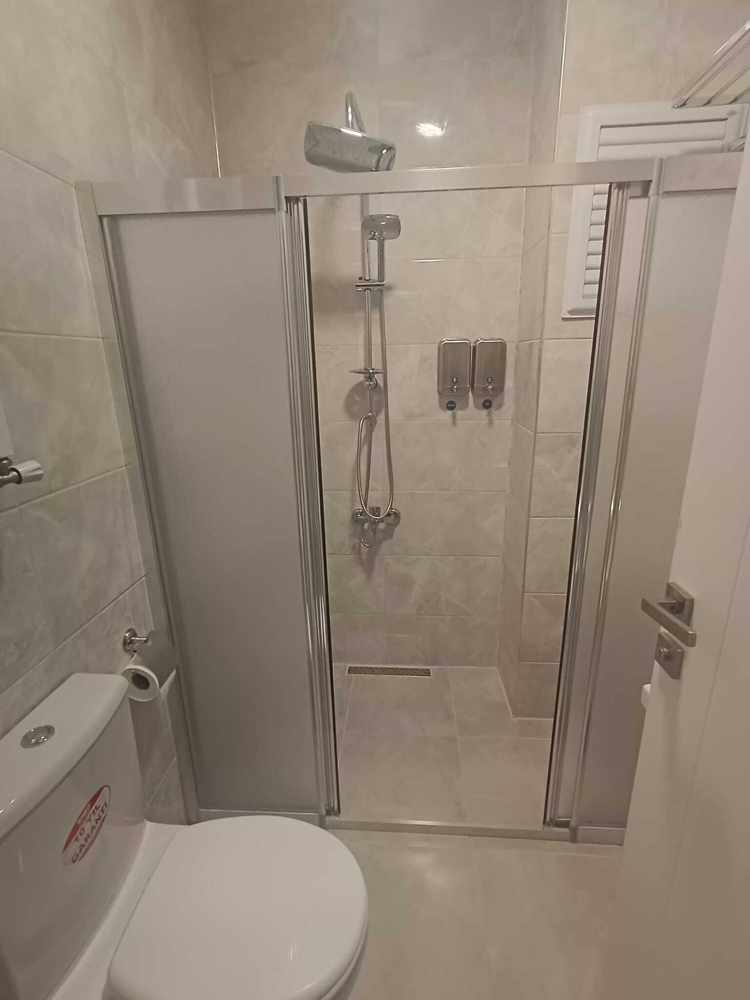 Un box de ducha con paredes de vidrio, un inodoro y un lavamanos.