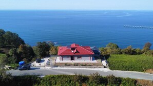 A coastal house with a red roof, a paved driveway, and a view of the sea. - Koçi Hotel (Pazar)