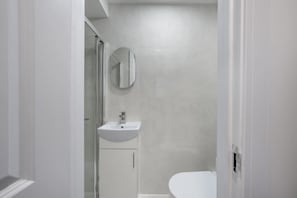 A bathroom with a shower, a sink, and a toilet. - Superior Ground Floor Studio in Knightsbridge (London)