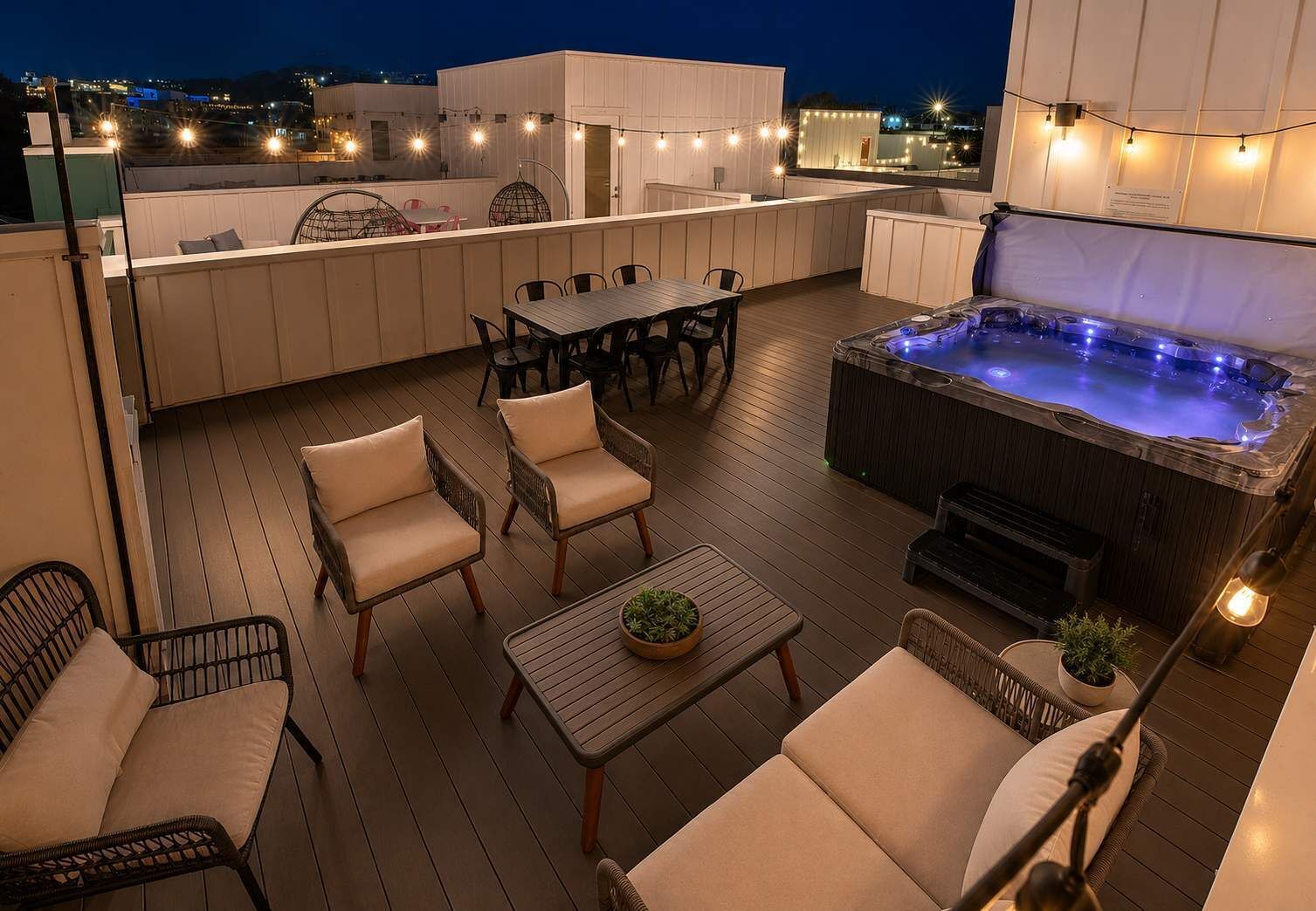 A rooftop terrace with a hot tub, seating area, and string lights.