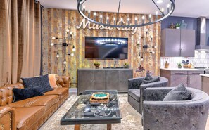 Ein modernes Wohnzimmer mit einer Ledersofa, einem Glastisch und einem flachbildfernseher, der an einer Holzwand angebracht ist.