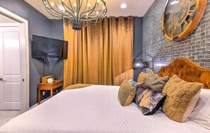 Ein Schlafzimmer mit einem großen Bett, einem an der Wand befestigten Fernseher, einer Uhr und einem einzigartigen Uhrendesign an der Wand.