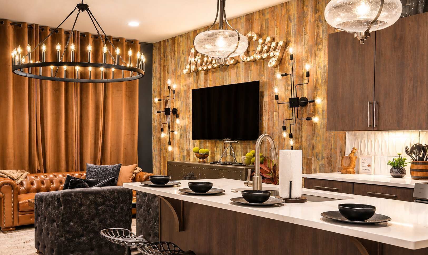 Una cocina moderna con una isla central, iluminación colgante y un televisor de pantalla plana montado en la pared.