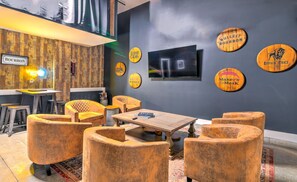 Ein moderner Lounge-Bereich mit einer Holzvertäfelung, einem Flachbildfernseher und mehreren runden Holztäfelchen.