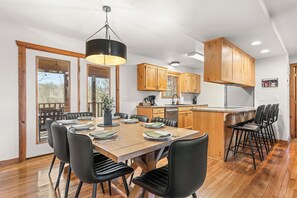 A modern kitchen with wooden cabinets, a dining area with a table and chairs, and a large window. - NEW! King Suites Private Baths, Near Silver Dollar (Branson West)