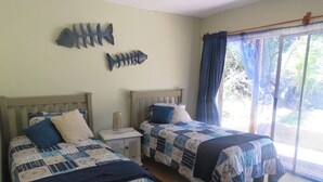 Een kamer met twee bedden, een nachtkastje, een vis decoratie en een raam met gordijnen.