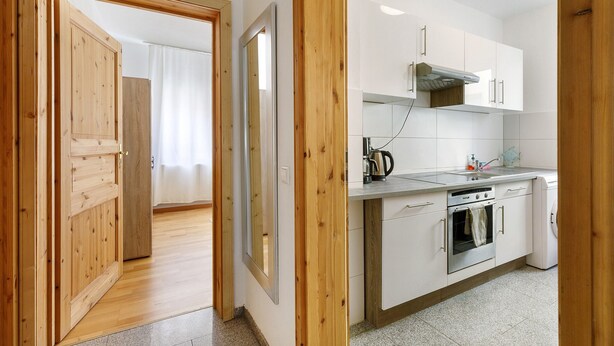 Une cuisine avec des meubles blancs, une cuisinière en acier inoxydable et un lave-linge.
