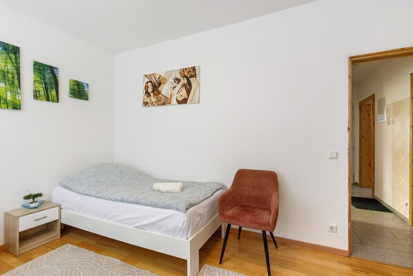 Une chambre à coucher comprenant un lit, une chaise, une table de chevet et des œuvres d’art murales.