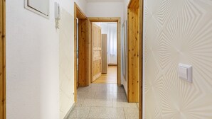 Un couloir avec des portes en bois, un mur orné d’un motif et un interrupteur.