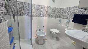 Un baño con cabina de ducha de vidrio, un bidé, un inodoro y un lavamanos.