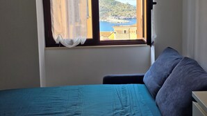 Una habitación con cama, ventana y vista al litoral.