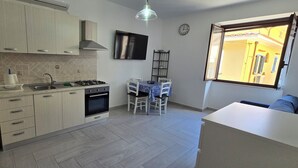 Una cocina moderna con lavadora, estufa, fregadero y comedor con sillas y mesa.