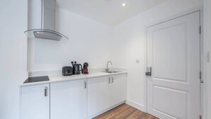 Une cuisine moderne avec des meubles blancs, une hotte de cuisinière en acier inoxydable, une machine à café et un évier.