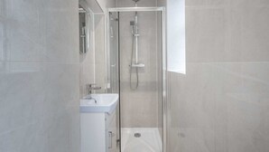 Une salle de bain moderne avec une douche à parois de verre, un lavabo blanc et un miroir.