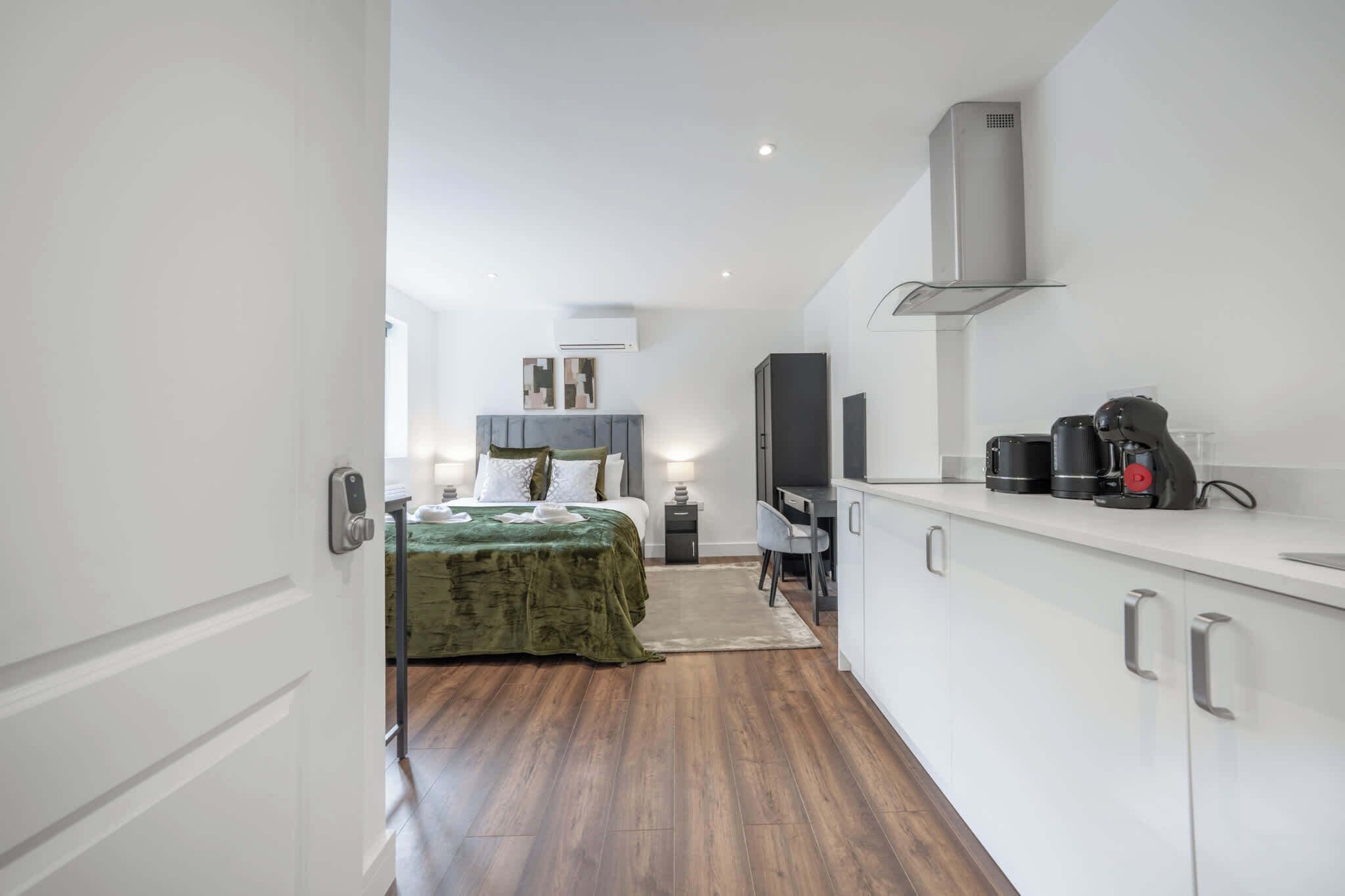 Una habitación de hotel moderna con una cama, un escritorio, una silla, un televisor y una kitchenette.