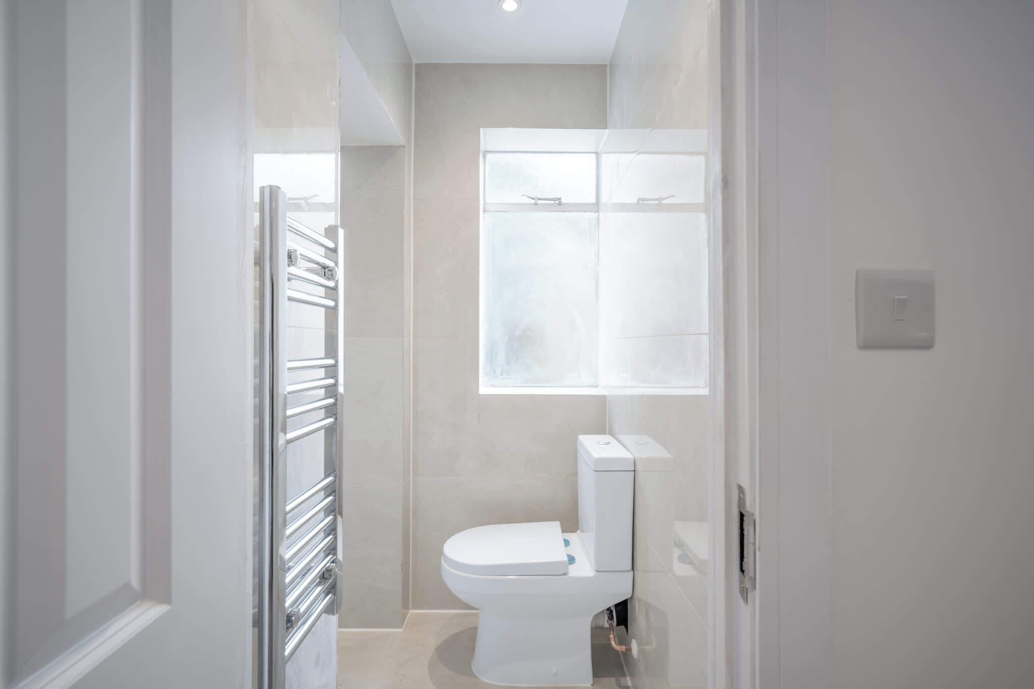 A modern bathroom with a toilet, a window, and a towel rack.