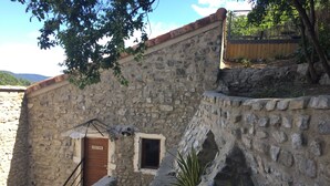 A stone building with a wooden door labeled 'NEW YORK,' a small window, and a staircase leading to an upper level. - Loft San Francisco (Baix)