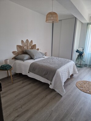 A modern bedroom with a bed, bedside table, lamp, and a large window.