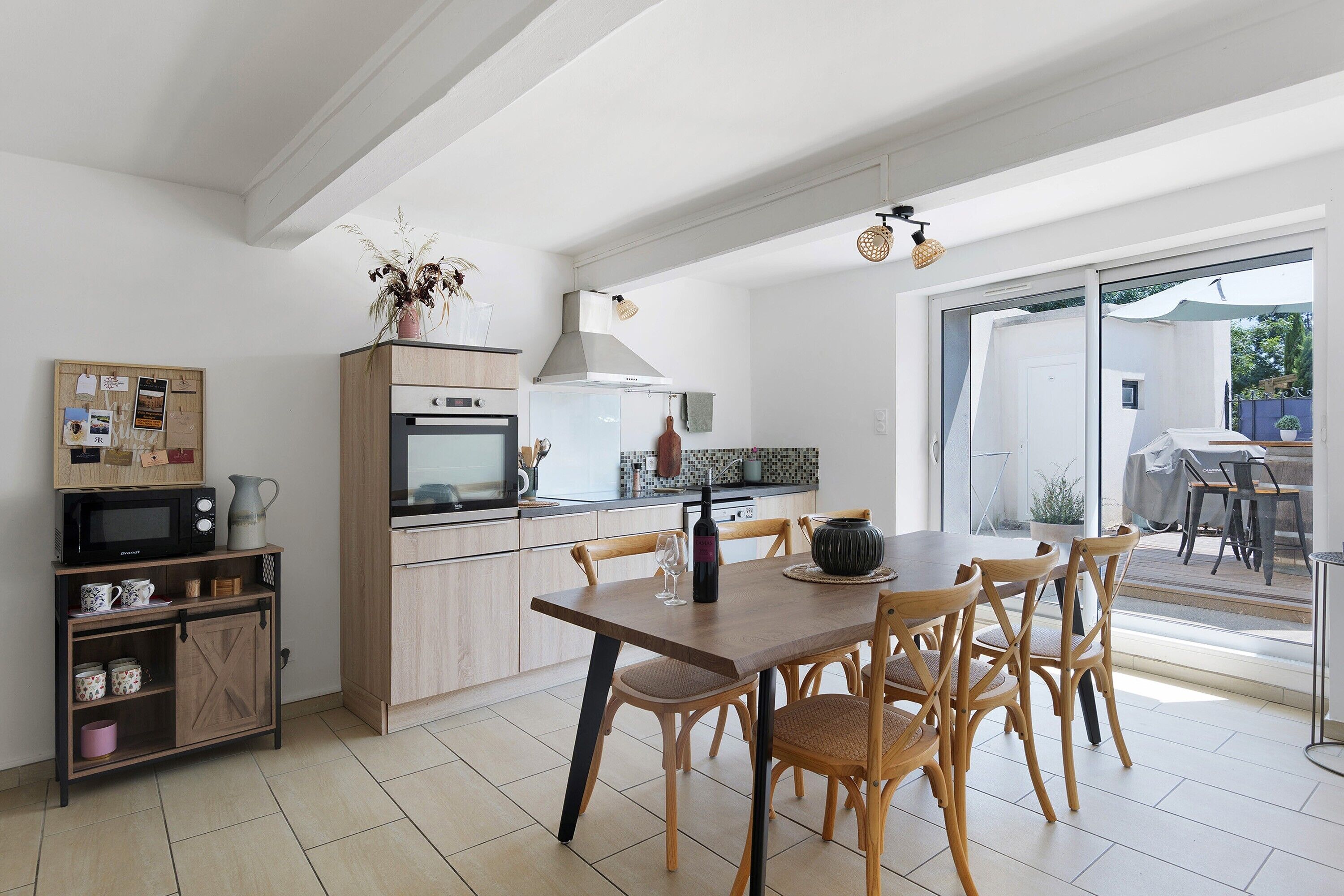 Une cuisine moderne avec un coin repas, des meubles en bois, un four à micro-ondes et une grande fenêtre.