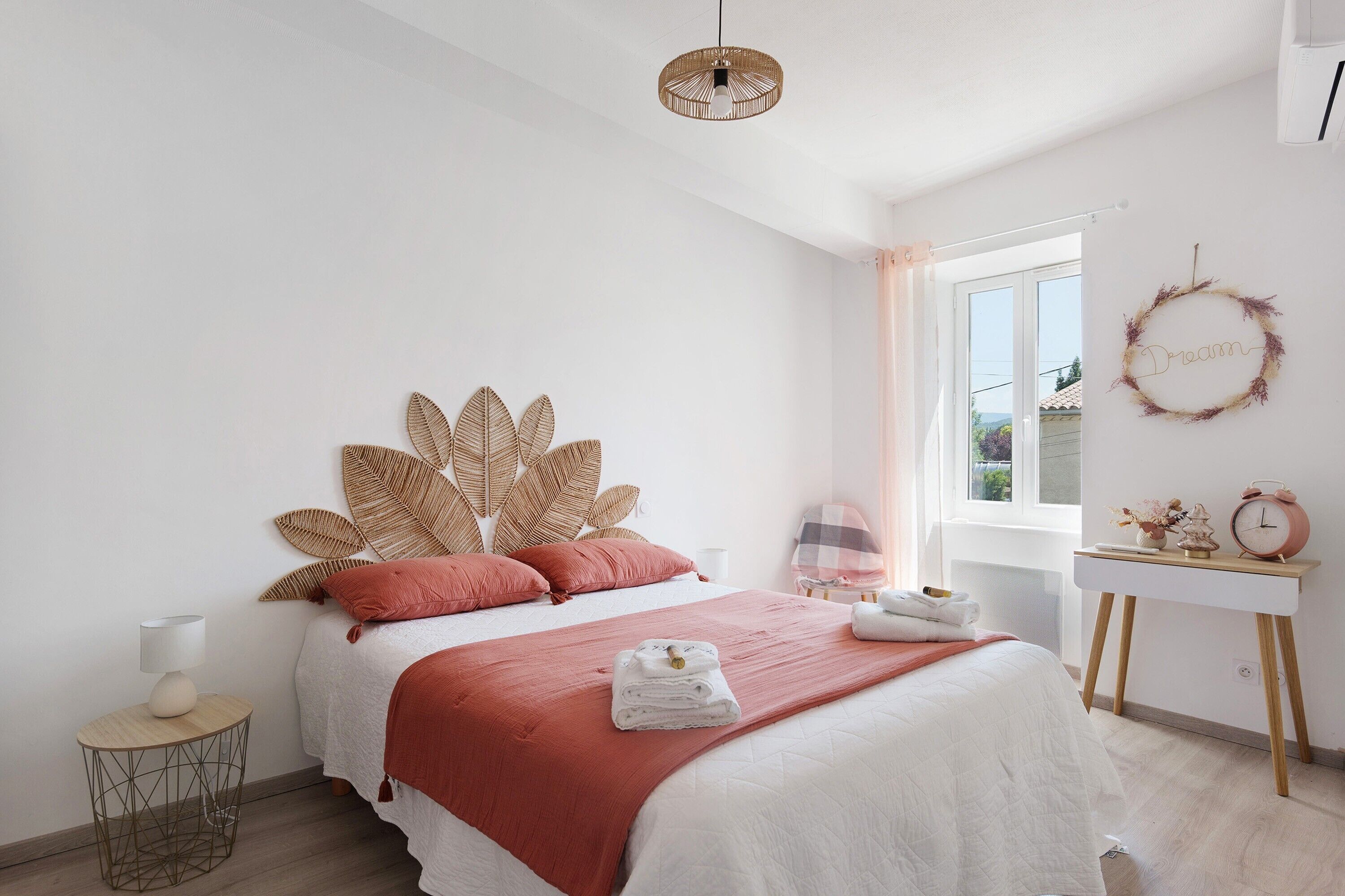 Un dormitorio con cama, mesita de noche, lámpara y ventana con vistas.