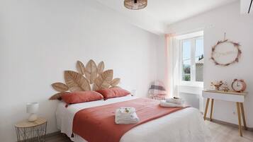 A bedroom with a bed, bedside table, lamp, and a window with a view.