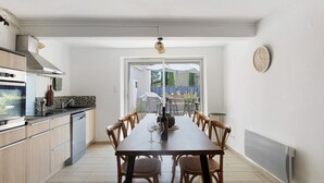 Una cucina moderna con mobili in legno, un tavolo da pranzo con sedie, un forno a incasso e un'ampia finestra.