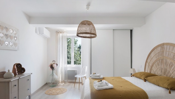 Una camera da letto con un letto, un comodino, una sedia e una grande finestra.