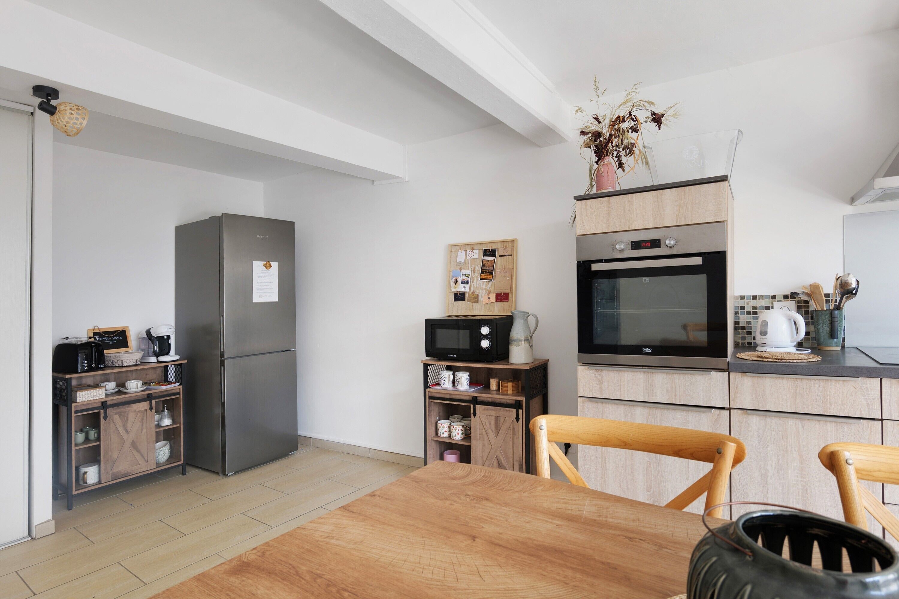 Eine moderne Küche mit Kühlschrank, Mikrowelle, Backofen und Holzschränken.
