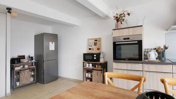 Eine moderne Küche mit Kühlschrank, Mikrowelle, Backofen und Holzschränken.