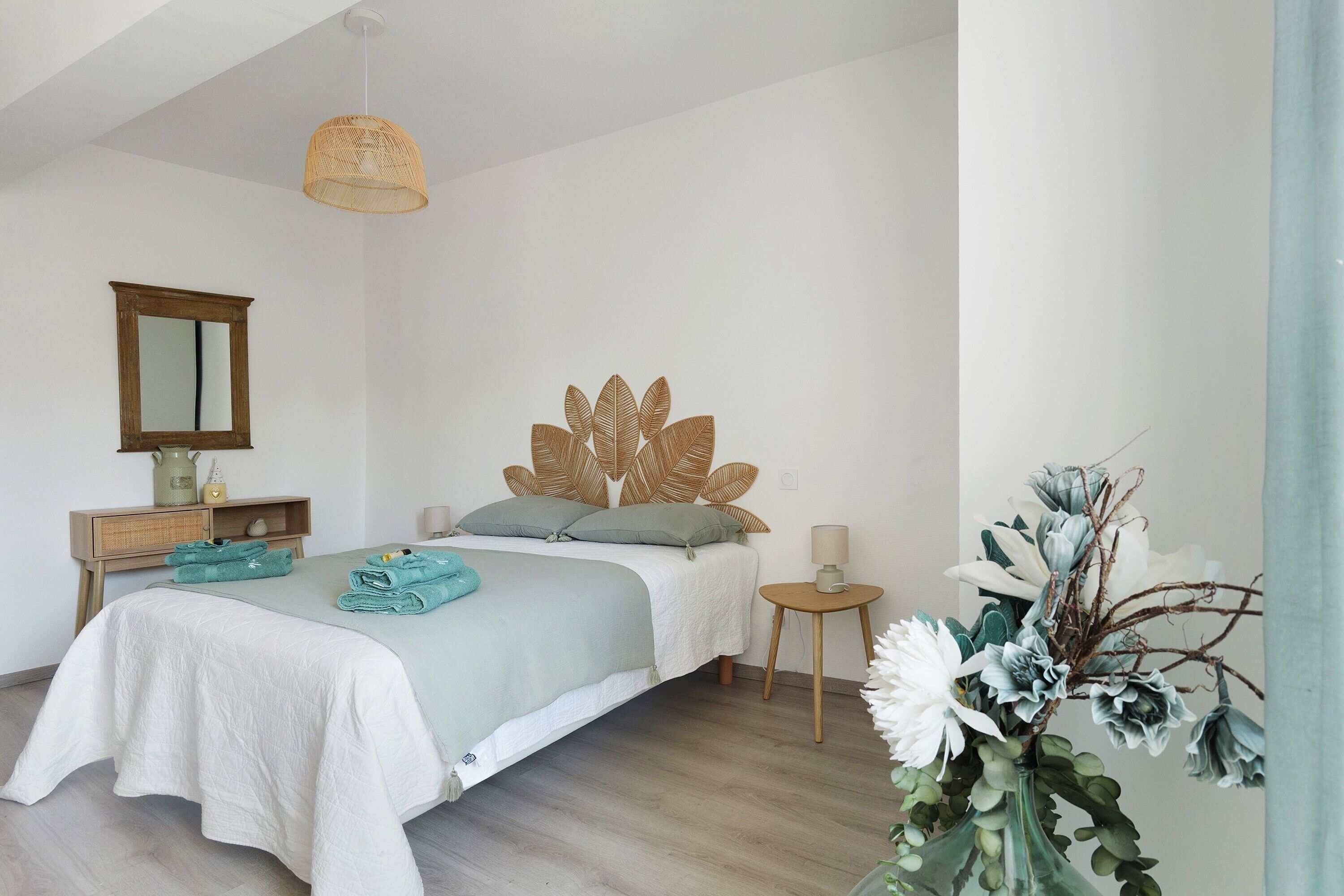 Un dormitorio con cama, mesitas de noche, un espejo y una lámpara colgante.