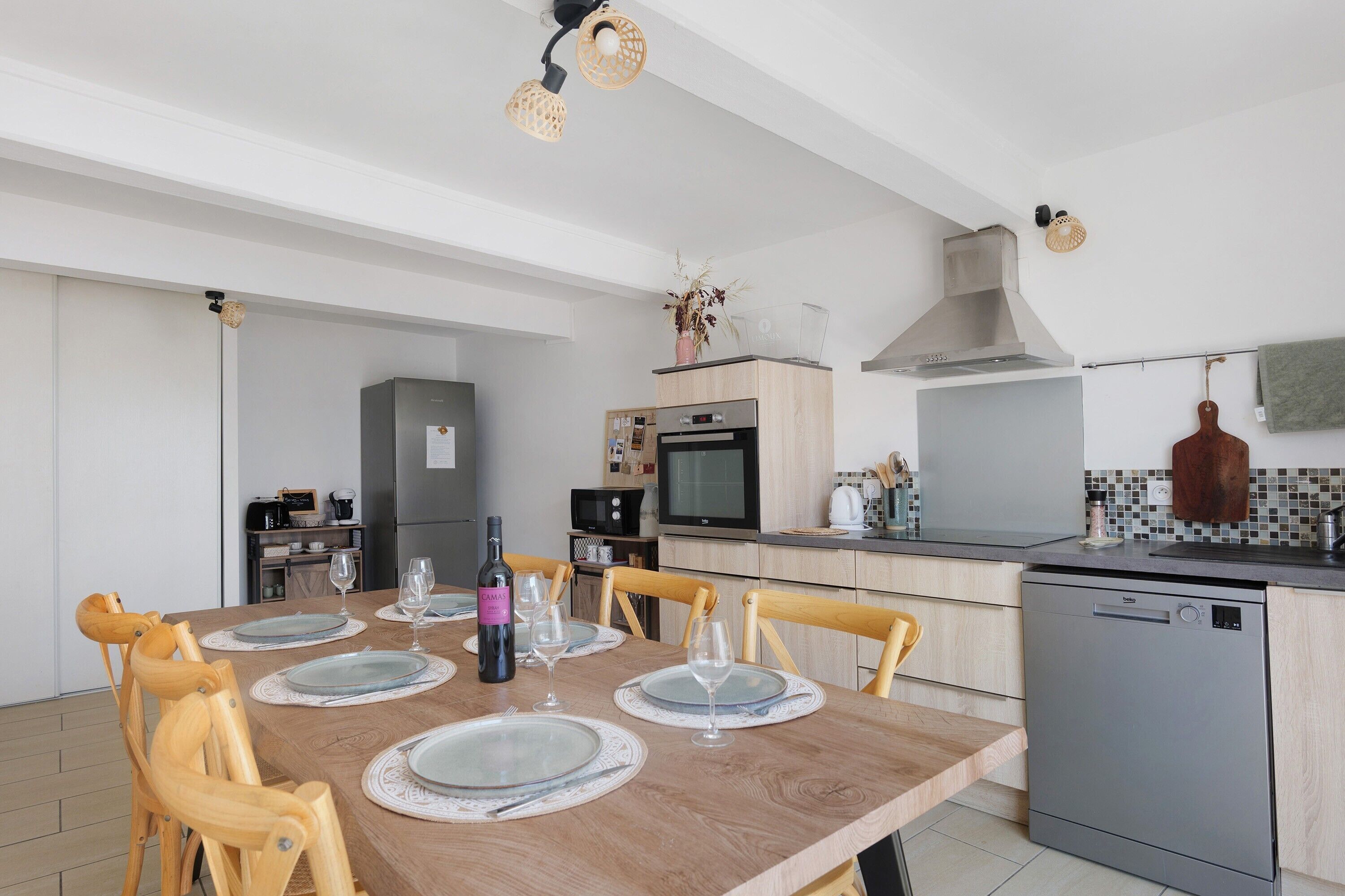 A modern kitchen with a dining area, wooden chairs, and a dishwasher.