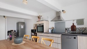 Una cucina moderna con un tavolo da pranzo in legno, sedie, lavastoviglie, microonde e fornello.