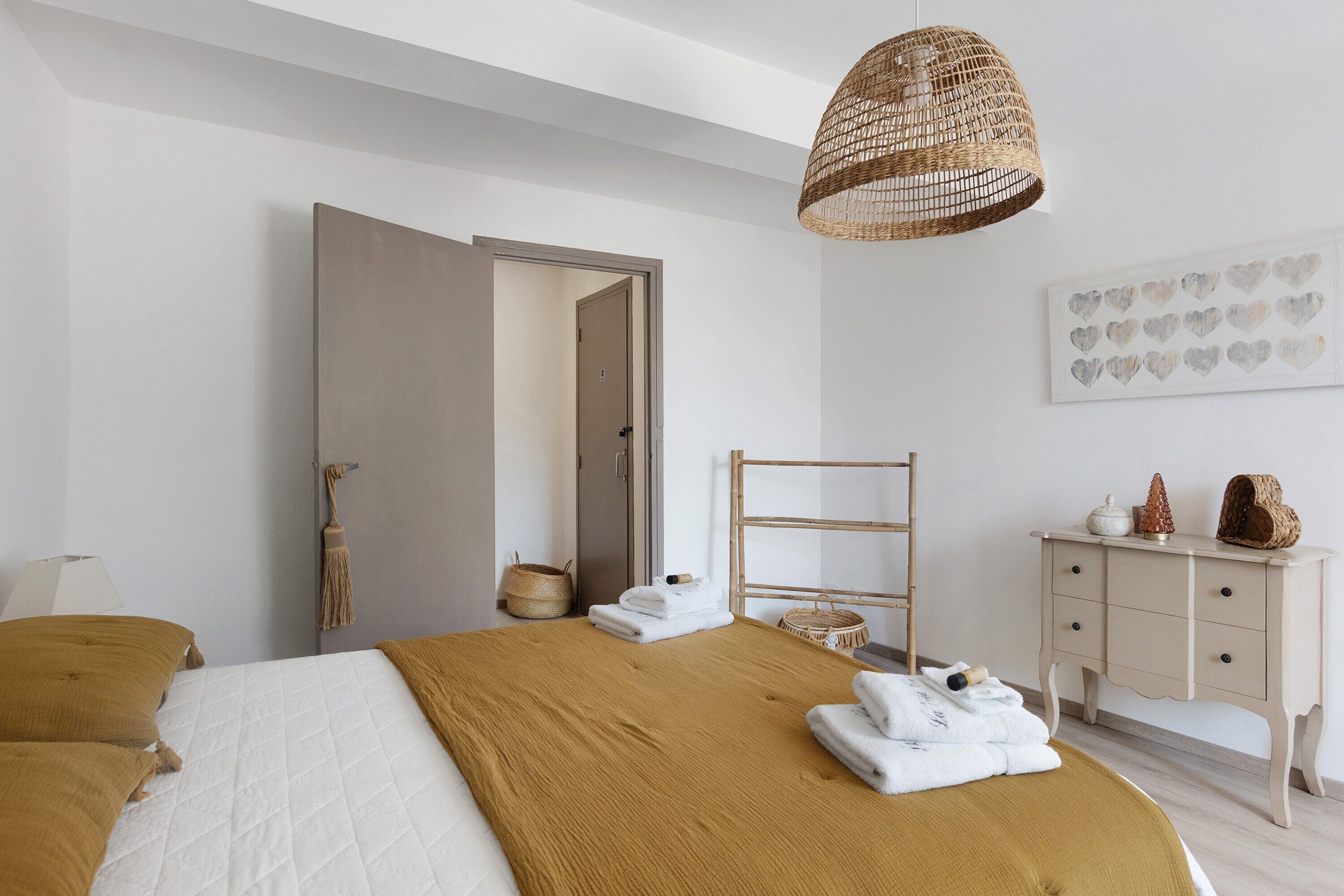 A bedroom with a bed, a bedside table, a wardrobe, a hanging basket, and a wall-mounted artwork.