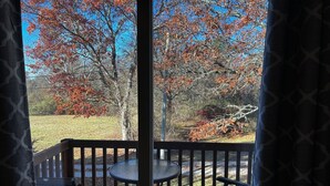 Une terrasse avec une table et des chaises, offrant une vue sur un paysage naturel avec des arbres et un ciel dégagé.