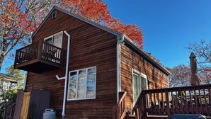 Une cabane en bois dotée d’un balcon, d’une terrasse couverte et d’un petit espace extérieur avec un barbecue.
