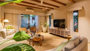 Ein großzügiges Wohnzimmer mit großem Fernseher, bequemen Sitzmöglichkeiten und Blick ins Freie.