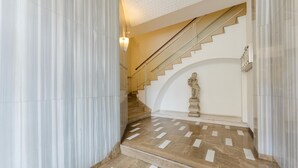A marble staircase with a handrail, a statue, and a light fixture. - Gaia's Flat - 15 min from Venice (Mestre)
