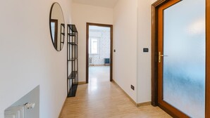 A hallway with a wooden door, a mirror, and a view into another room. - Gaia's Flat - 15 min from Venice (Mestre)