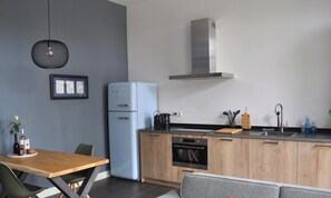 Eine moderne Küche mit einem blauen Kühlschrank, Holzschränken, einem eingebauten Ofen und einem Edelstahl-Spülbecken.