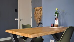 Puisesta ruokapöydästä ja tuoleista koostuva ruokailuryhmä, alkoholipullo ja kynttilä aluslautasella.