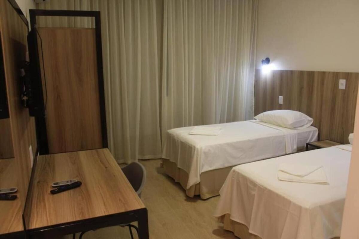 Une chambre d’hôtel avec deux lits simples, un bureau en bois et un téléviseur.