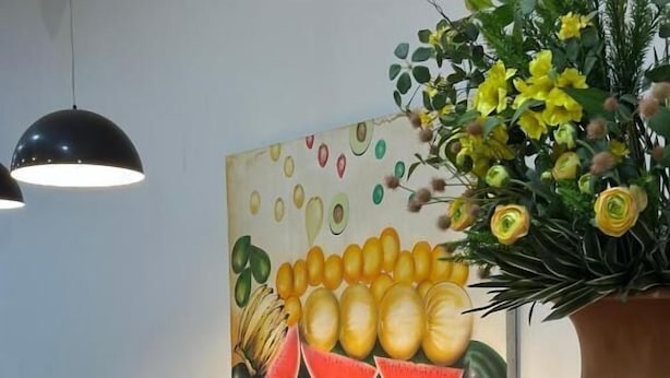 A counter with a variety of fruits, a coffee machine, and a painting of fruits. - Hotel Oscar Gold Janaúba (Janaúba)