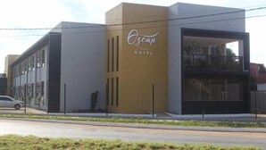 A modern hotel building with a prominent yellow and white facade, a large glass entrance, and a visible outdoor seating area. - Hotel Oscar Gold Janaúba (Janaúba)
